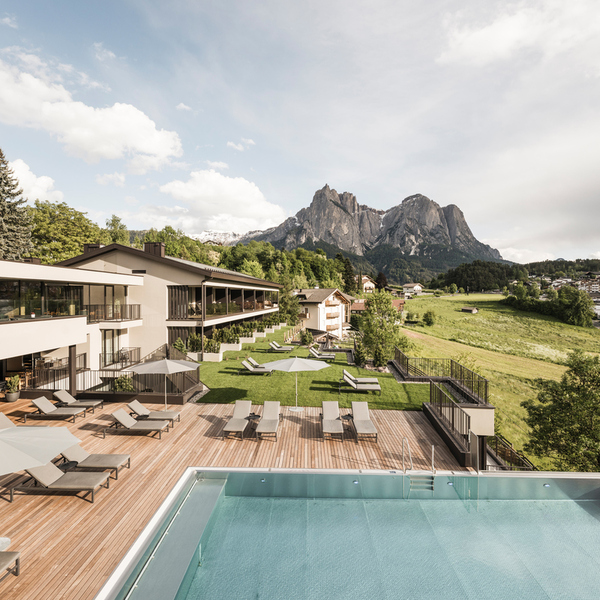 Hotel Alpenflora sun deck, loungers and outdoor pool with views of the Schlern peaks in South Tyrol